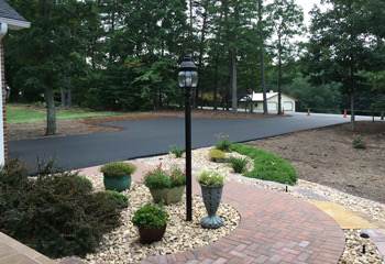 New asphalt drive beside a brick walkway