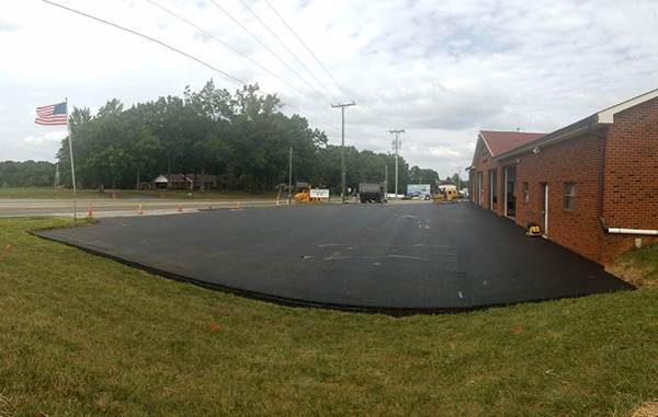 Freshly paved asphalt lot beside a brick building