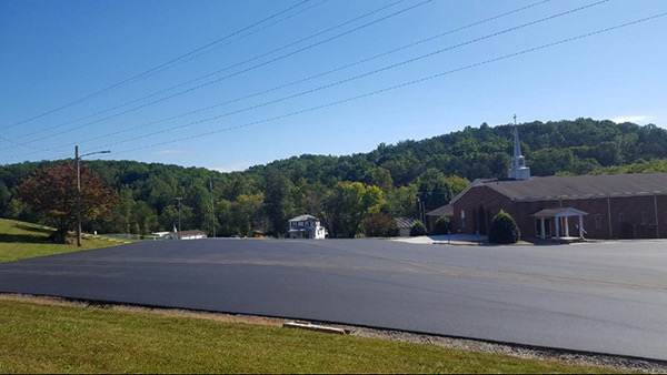 Newly paved parking lot with wooded hills behind it
