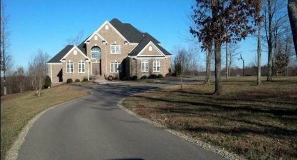 New asphalt driveway curving up to a large home