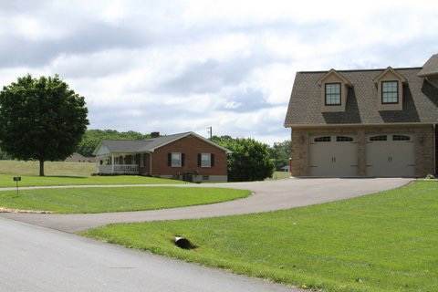 Dark asphalt driveway leading to a two-car garage