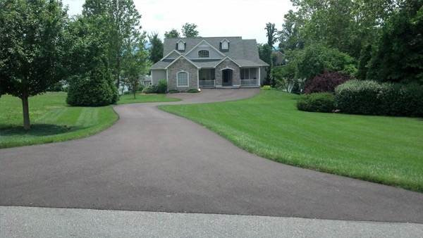 Asphalt driveway curving through a green lawn