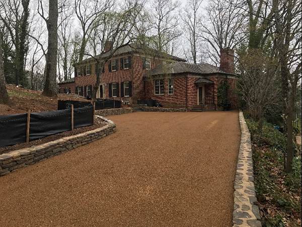 Surface-treated driveway edged with stonework at a brick home